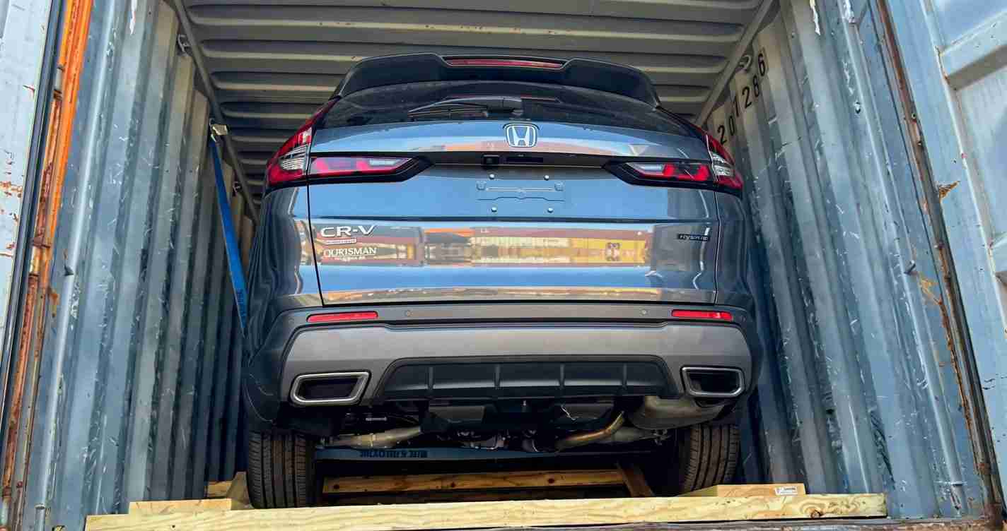Blue Honda CR-V viewed from the rear inside a metal shipping container on wooden supports