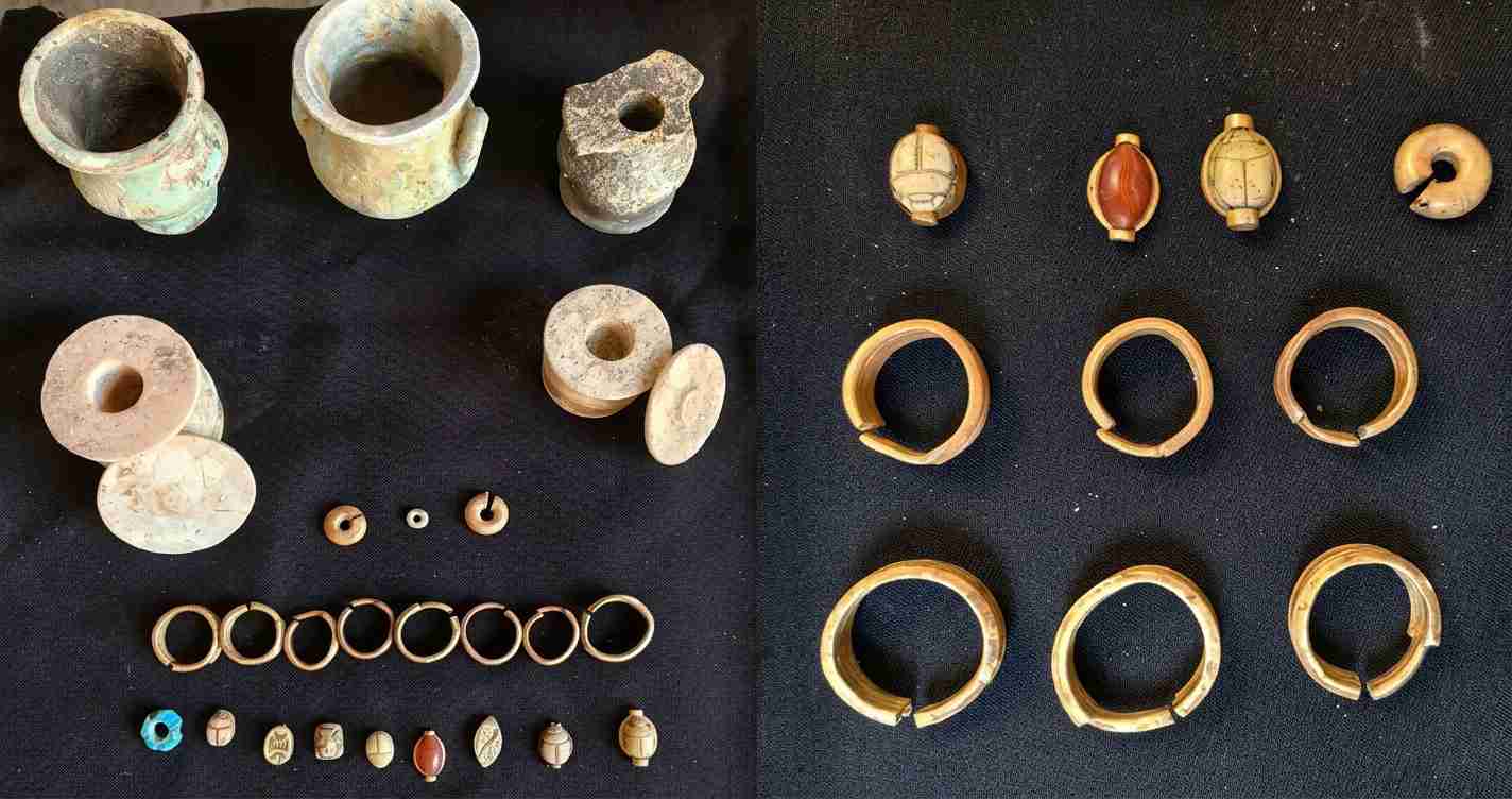 Assorted ancient bronze rings, beads, and small ceramic spindles laid out on a dark cloth; some rings are broken and there are carved beads at the bottom left. Left side shows pottery fragments and spindle weights, right side shows circular bracelets and bead caps on display table.
