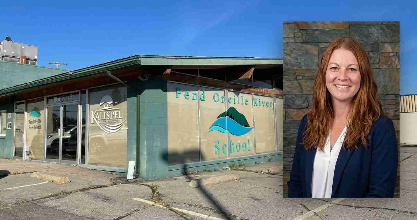 Exterior view of Pend Oreille River School building with teal walls and large glass storefronts; a smiling red-haired woman in a navy blazer stands beside a stone wall on the right.