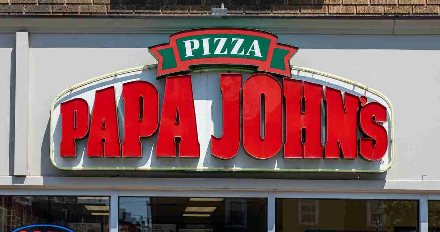 Storefront sign for Papa John’s Pizza with large red letters spelling PAPA JOHN’S and a green banner reading PIZZA above.