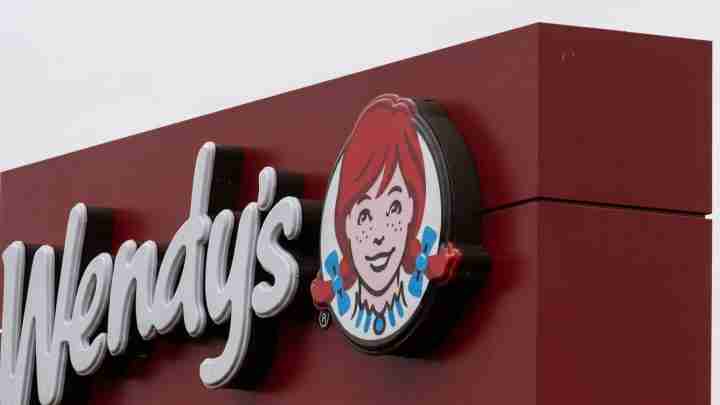 Wendy's restaurant sign with a maroon exterior and the brand's smiling red-haired girl logo,