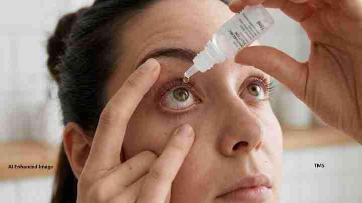 Close-up of a person applying eye drops to their eye with a dropper in hand.